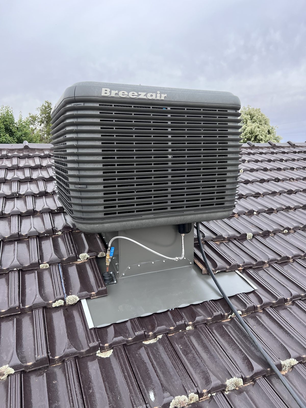 Breezair evaporative cooler on a tile roof